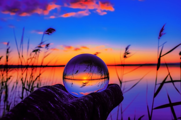 Foto gratuito hermosa toma de enfoque selectivo de una bola de cristal que refleja la impresionante puesta de sol