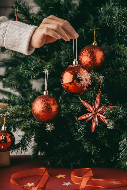 Foto gratuito mano de mujer irreconocible con adorno delante del árbol de navidad