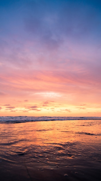 Foto gratuito tiro vertical de un cuerpo de agua con el cielo rosado durante la puesta del sol. perfecto para un fondo de pantalla.