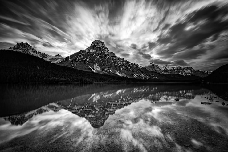 Foto la majestuosa montaña rocosa y su reflejo de un plácido lago en escala de gris