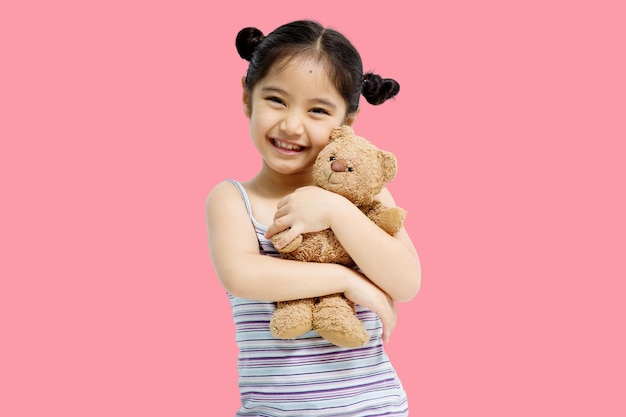 ฟรี Photo เด็กหญิงเอเชียตัวน้อยน่ารักกอดตุ๊กตาหมีแยกจากพื้นหลังสีชมพู