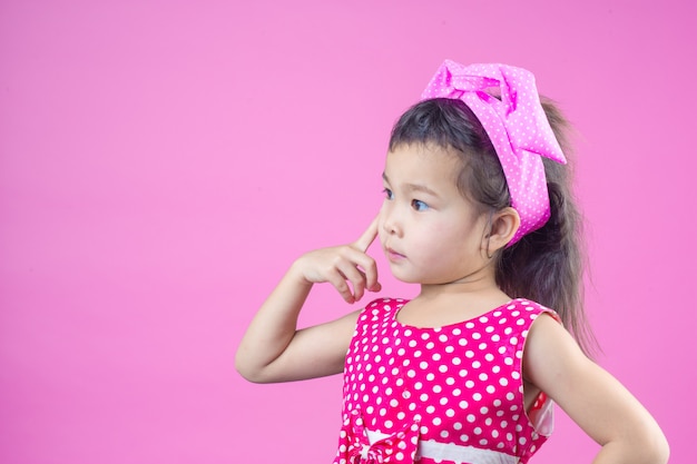 ฟรี Photo เด็กสาวน่ารักสวมเสื้อลายทางสีแดง ผูกโบว์สีชมพูบนศีรษะและสีชมพู