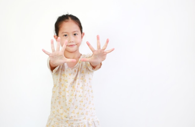 Photo ภาพเหมือนของเด็กหญิงตัวเล็ก ๆ ชาวเอเชีย แสดงท่าทางเอามือแบออกบนพื้นหลังสีขาว เน้นที่มือเด็ก