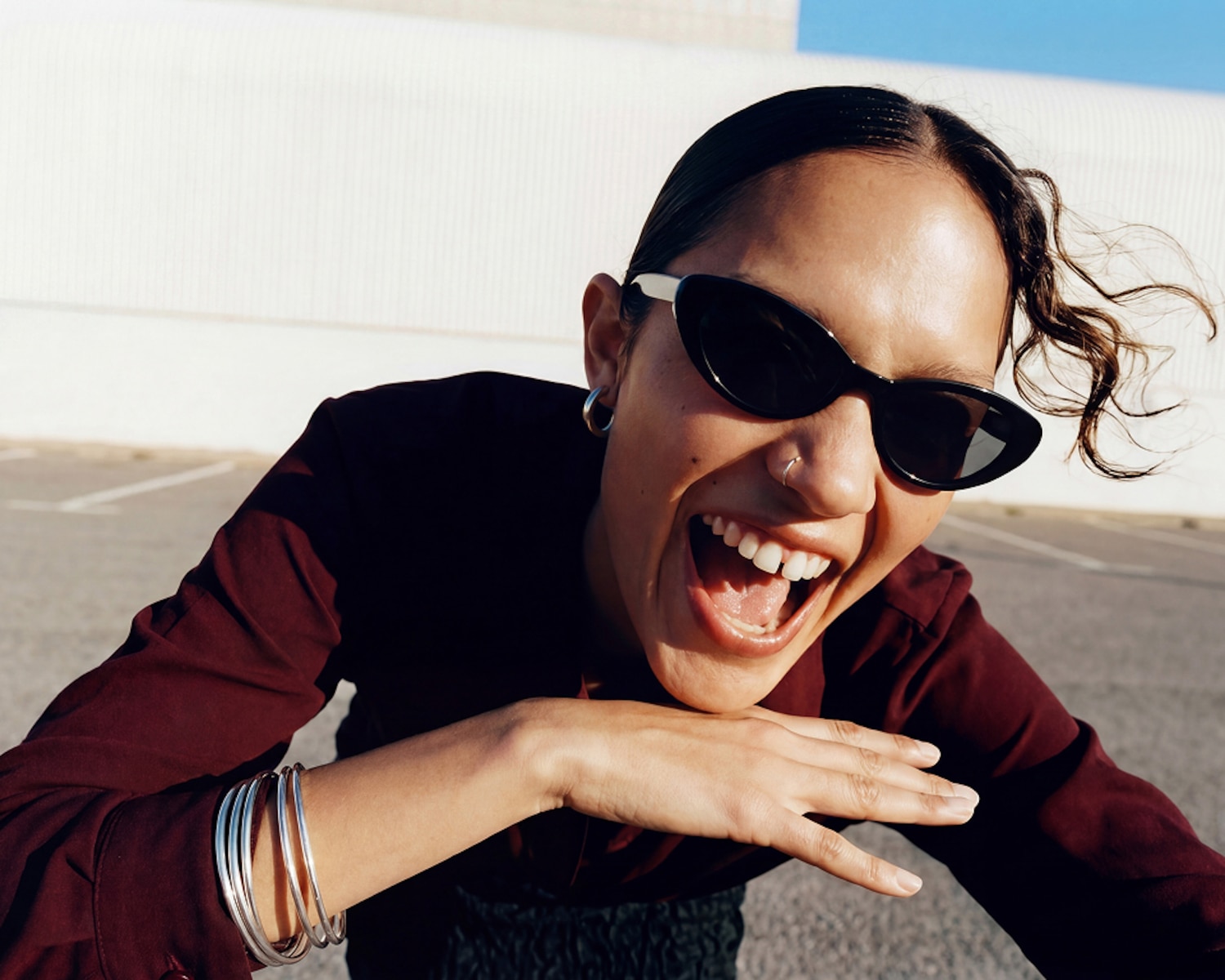 Laughing woman in black sunglasses leaning toward the camera