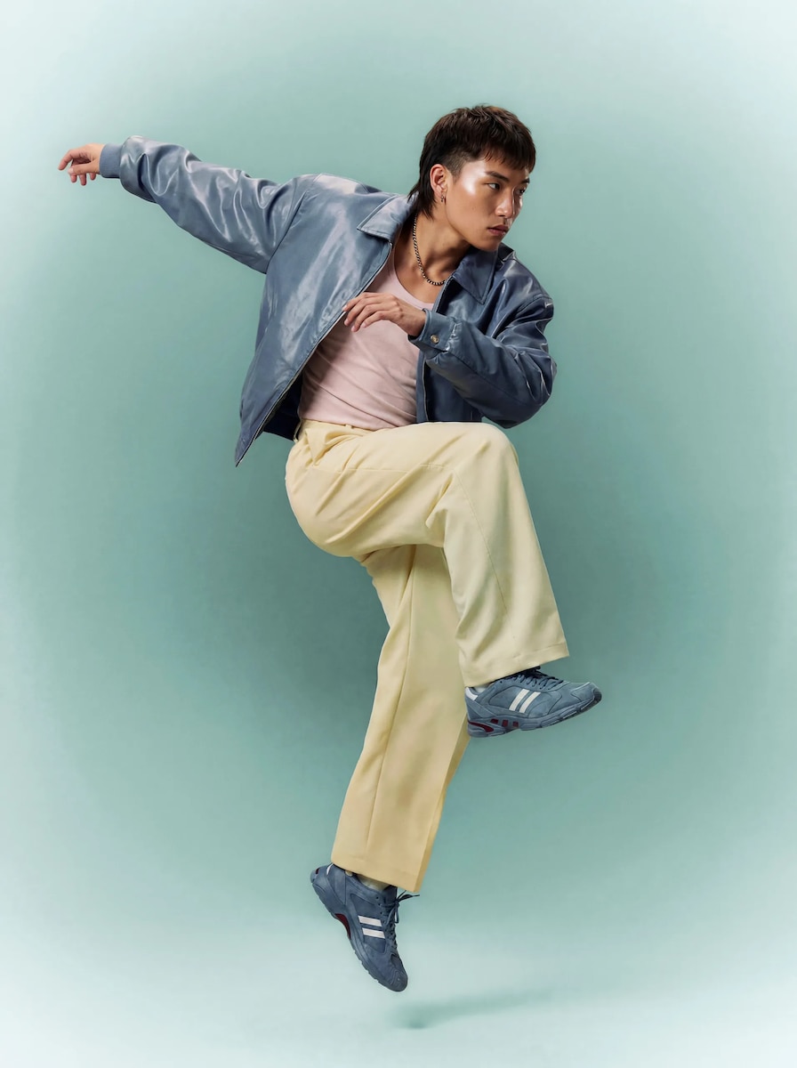 A man in a blue jacket striking a pose mid-step against a teal backdrop, generated with Kling 3.0 Motion Control on Magnific